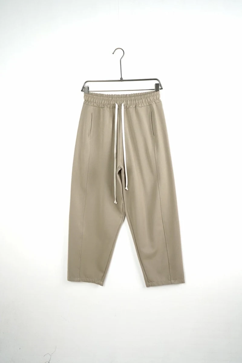 Vedere frontală pe umeraș a modelului: pantaloni bărbați bej baggy cu cusături frontale.