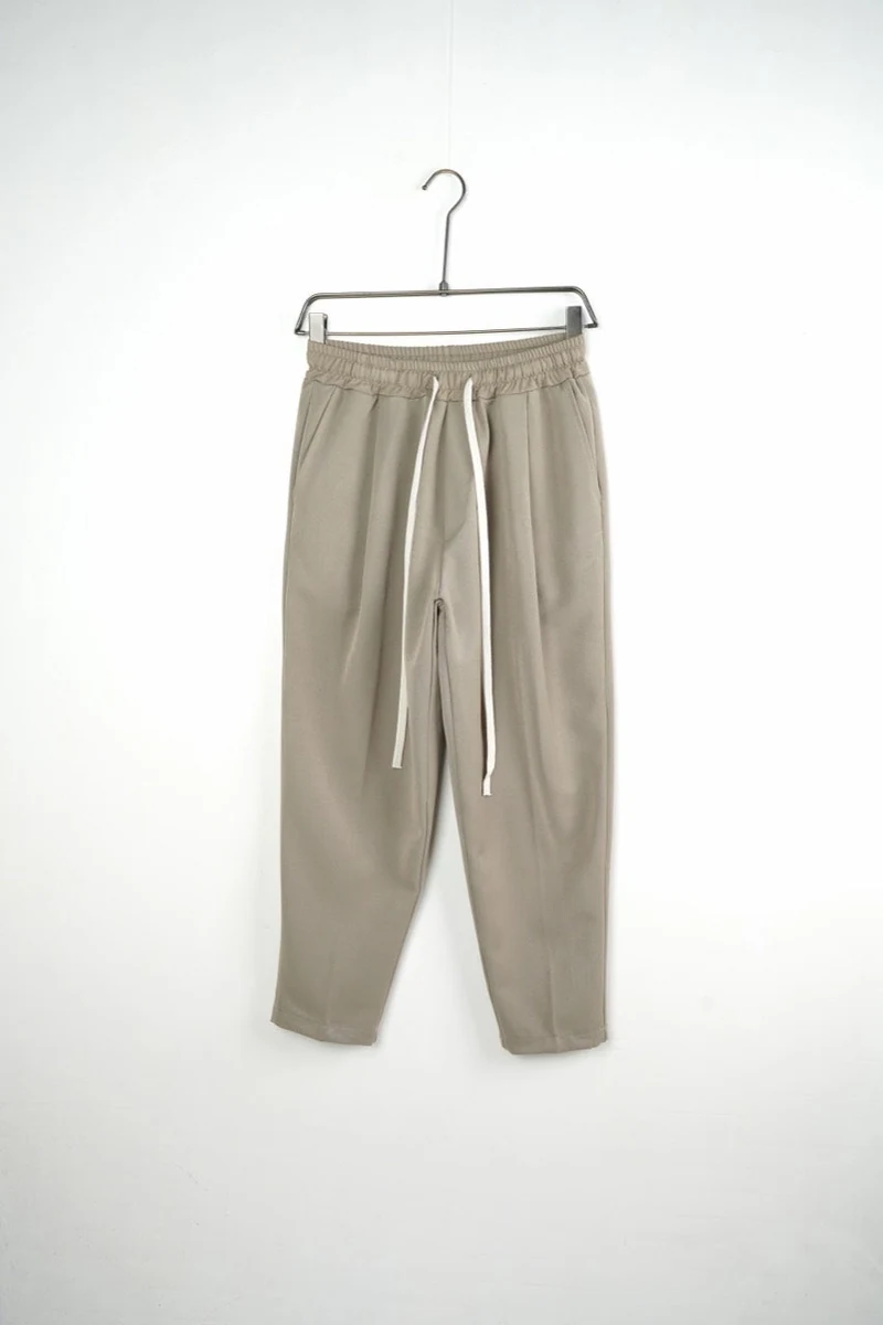 Pantaloni bărbați bej carrot fit — vedere frontală pe umeraș.