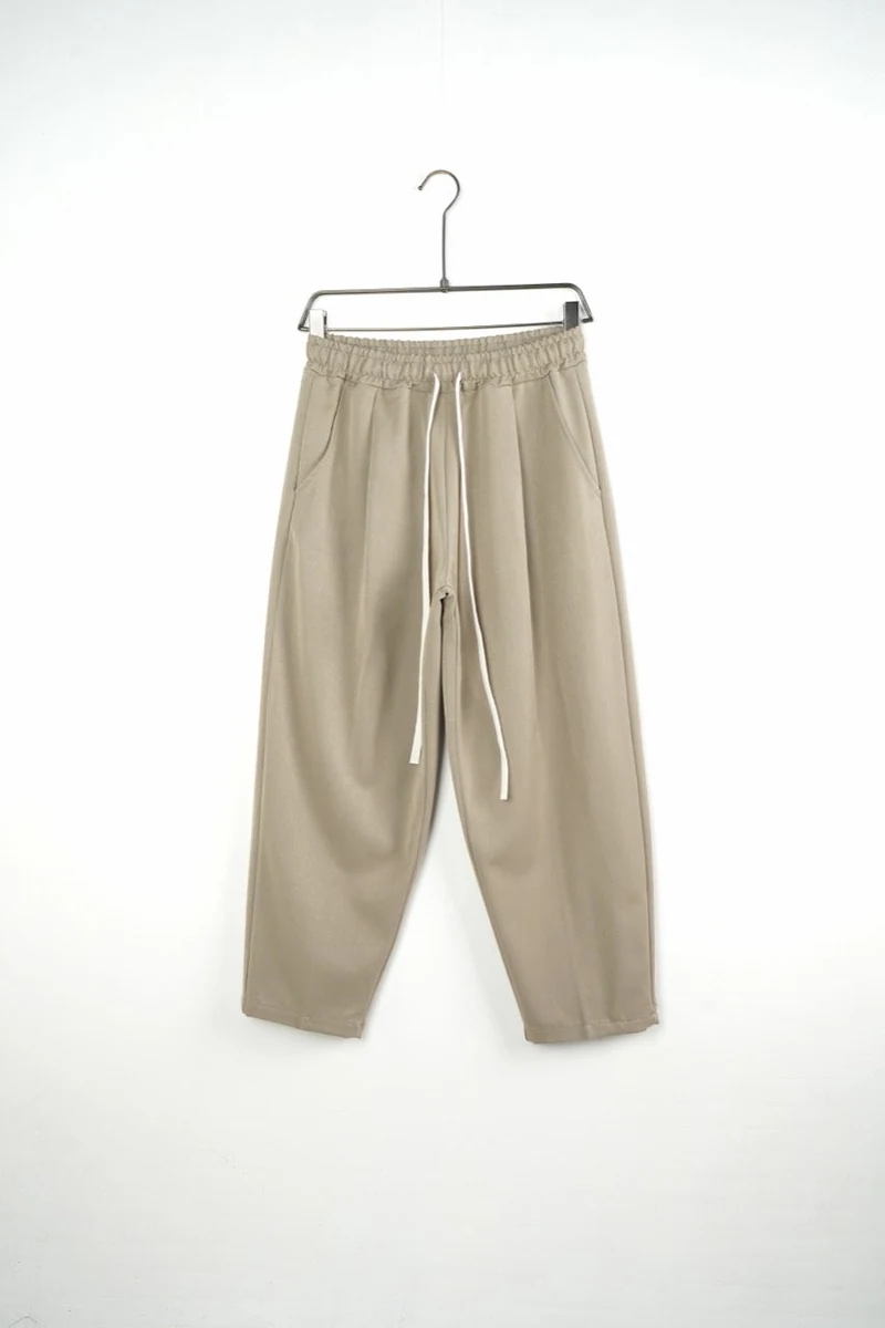 Vedere frontală pe umeraș: pantaloni bărbați bej largi baggy.