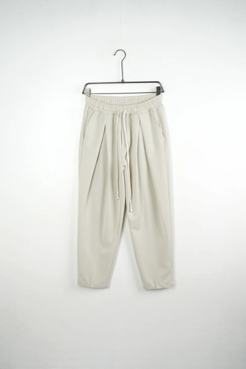 Vedere frontală pe umeraș a modelului: pantaloni bărbați crem cu pense și talie elastică.