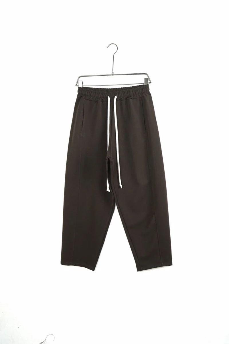 Pantaloni bărbați maro baggy cu cusături frontale; vedere frontală pe umeraș pentru compararea croielii.