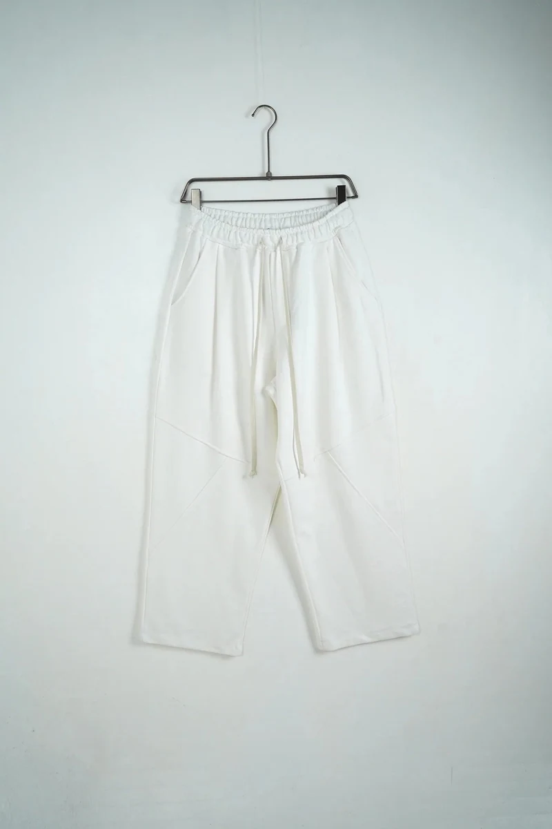Pantaloni largi albi de trening pentru bărbați cu model; vedere frontală pe umeraș pentru compararea croielii.