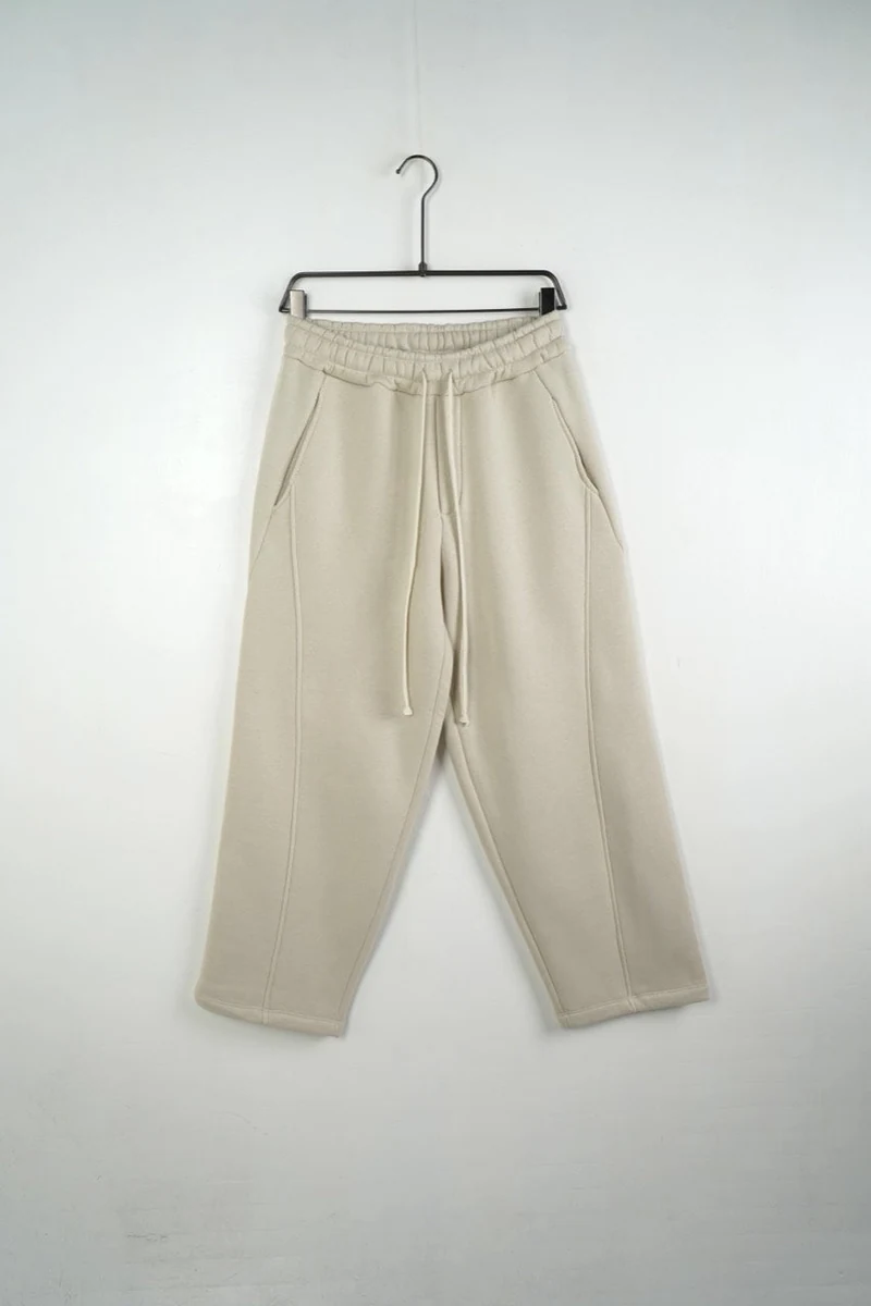 Vedere frontală pe umeraș a modelului: pantaloni largi bărbați bej felpați cu șnur lung.