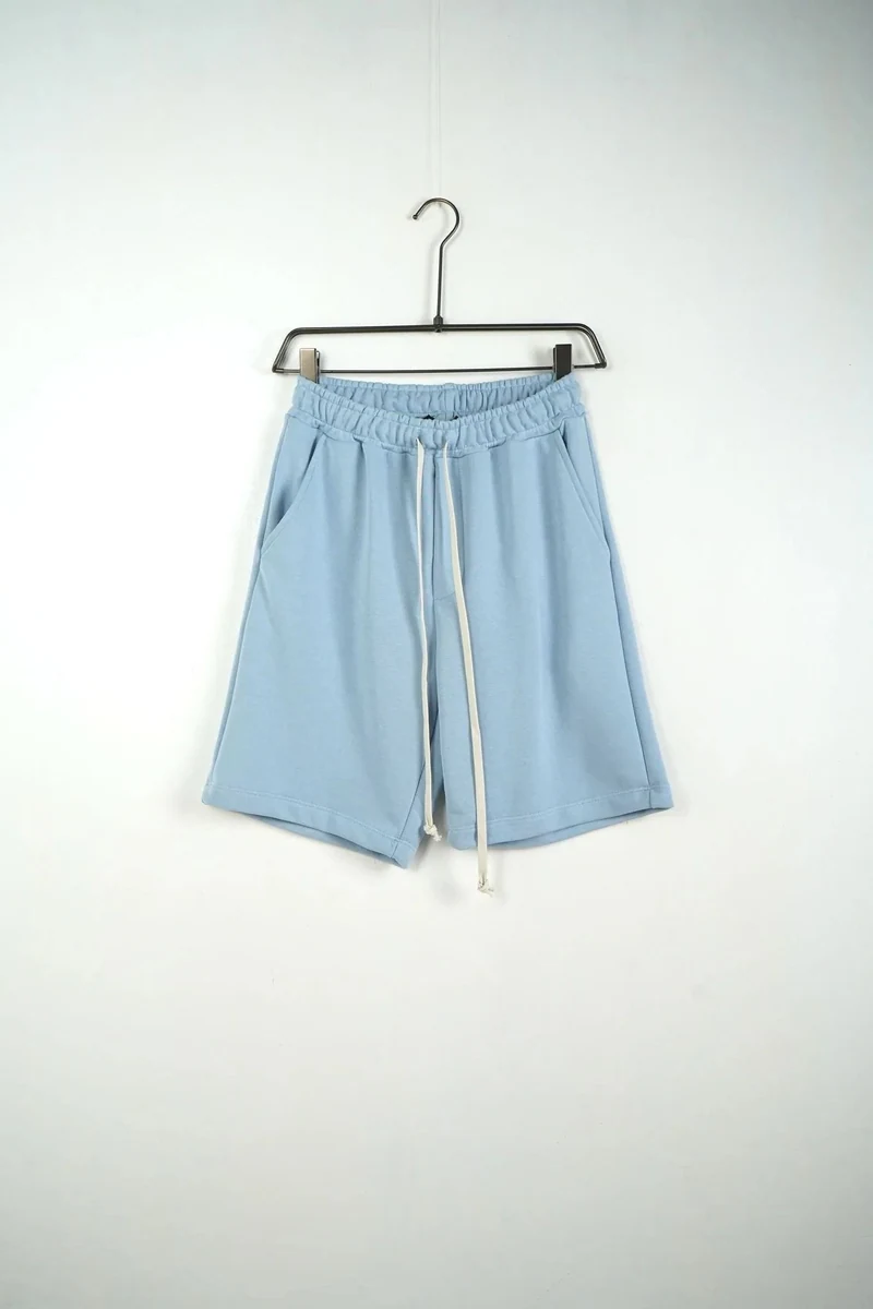 Vedere frontală pe umeraș: pantaloni scurți unisex din bumbac albastru deschis.