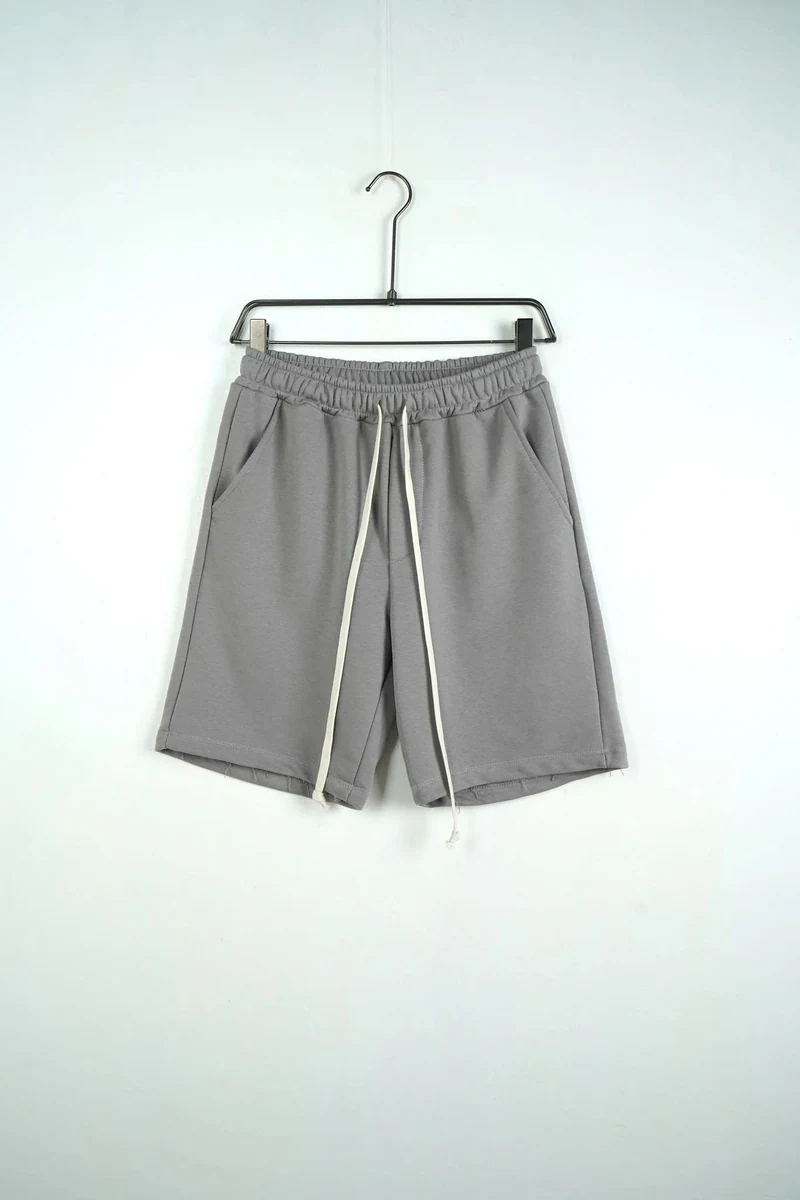 Vedere frontală pe umeraș a modelului: pantaloni scurți unisex din bumbac gri deschis.