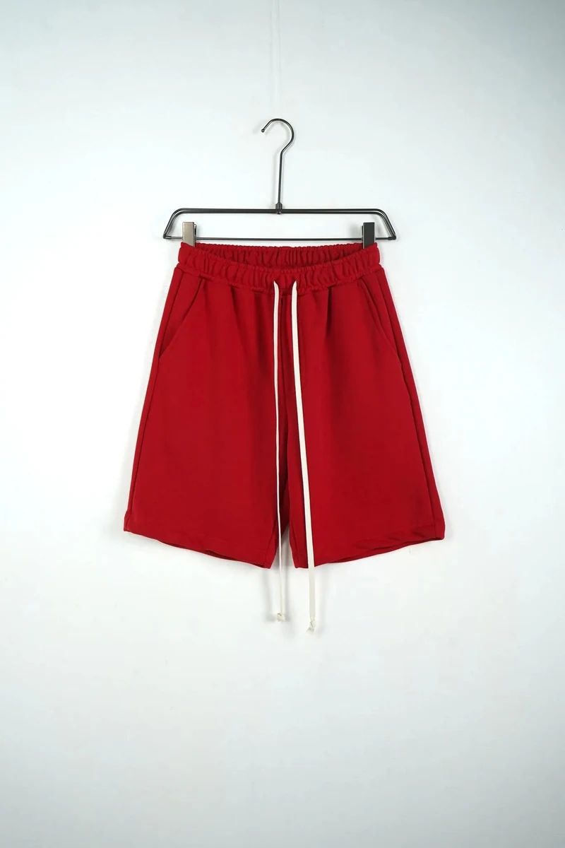 Pantaloni scurți unisex din bumbac rosii, vedere frontală pe umeraș, în catalogul editorial.